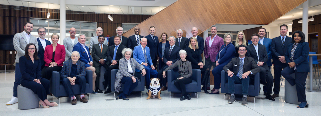 group of 29 men and women in business clothing posed in chairs and standing, with Butler live mascot bulldog